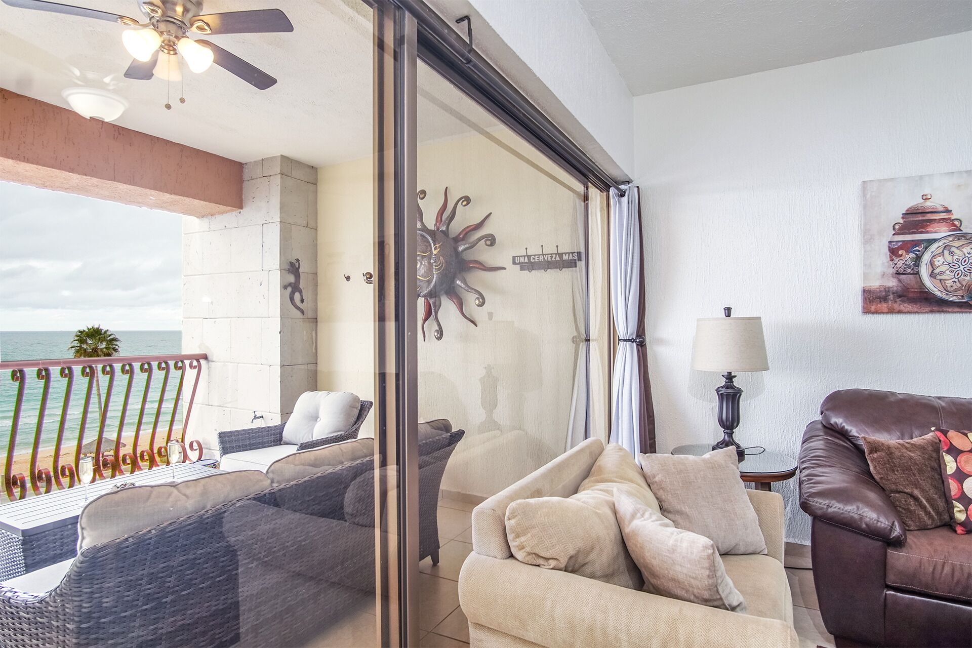 A living room with a glass door leading to a balcony overlooking the ocean.