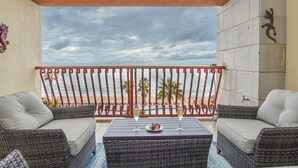 Un balcone con mobili in vimini, un tavolo con due bicchieri di champagne e vista sulla spiaggia e sulle palme.