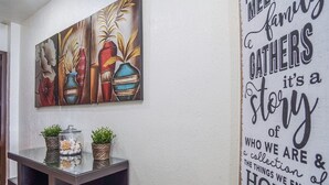 Un muro con un dipinto decorativo raffigurante vasi e un testo importante che recita: “La famiglia in bagno è la storia di chi siamo e delle cose che ci piacciono a casa.”