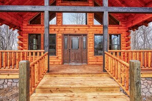 A log cabin with a wooden porch and a stone foundation.
