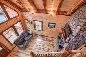 Un interior de madera con chimenea de piedra, un sofá y una escalera.