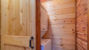 A wooden interior with a door, a white appliance, and a curved wooden wall. - Bluebonnet Luxury Cabin - in the Hocking Hills (Logan)