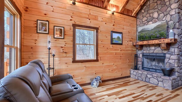 A log cabin interior with a stone fireplace, wooden walls, and a leather sofa. - Bluebonnet Luxury Cabin - in the Hocking Hills (Logan)