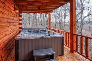 A wooden cabin with a hot tub on a deck.