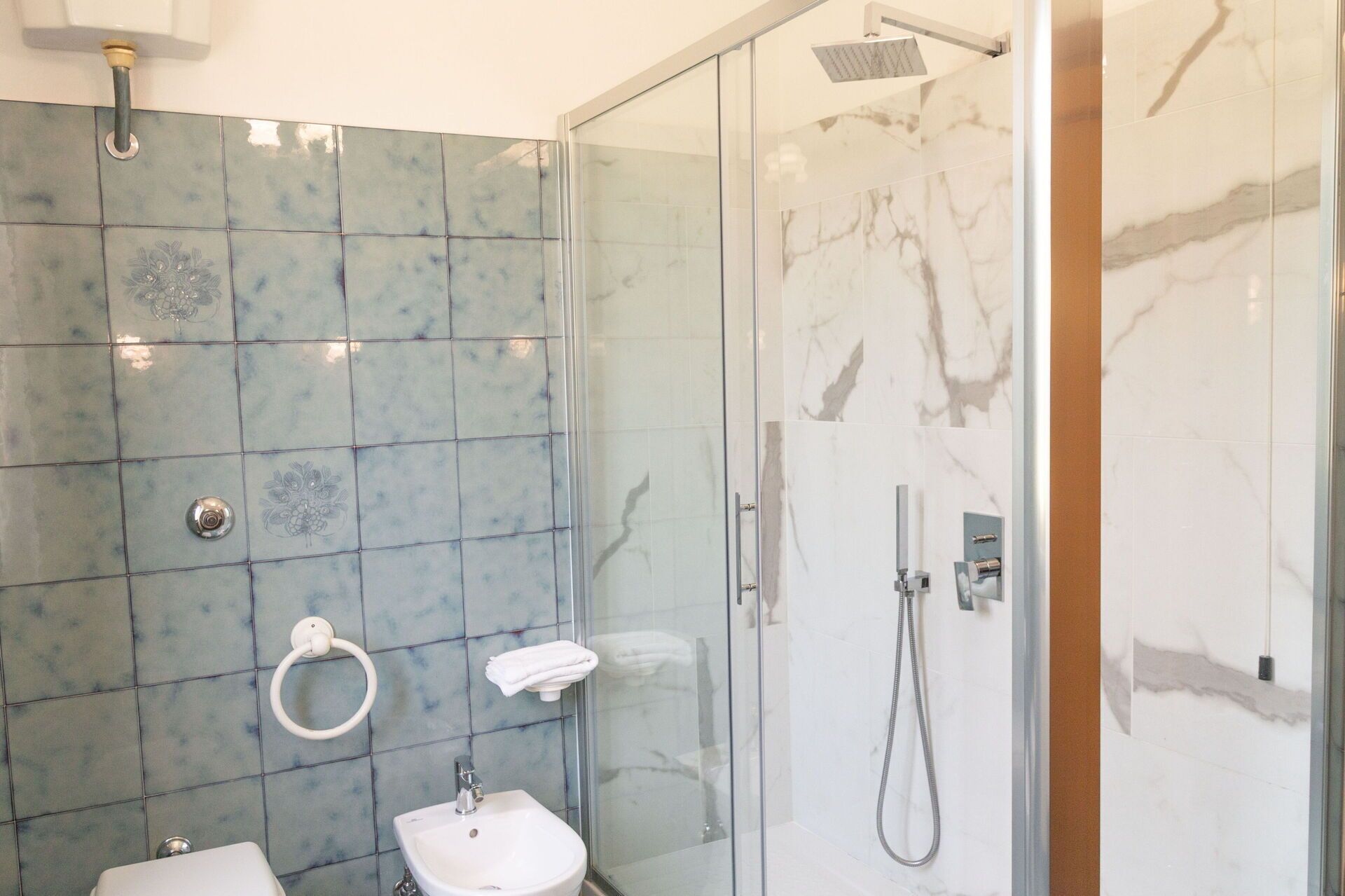 Et badeværelse med glasbrusekabine, vask og toilet.