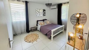 Une chambre à coucher avec un lit, une table de chevet, une lampe et une fenêtre avec des rideaux.