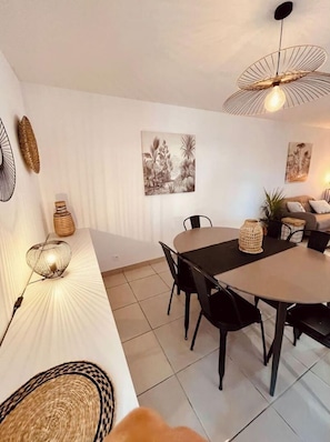 A dining area with a round table, black chairs, and a hanging light fixture.