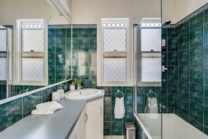 Bathroom features a large mirror, sink, and glass-enclosed shower.