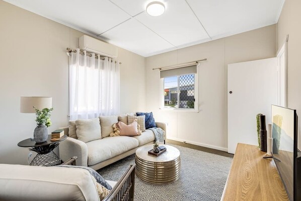 Relax in this cozy living space with a comfortable sofa, coffee table, and mounted TV.