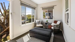 Ein kleiner Balkon mit einer Sitzecke, zwei Stühlen, einem Tisch und einem Blumentopf.