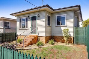 Stroll up to the charming entrance, flanked by two windows, and step into a cozy home surrounded by a lush garden.