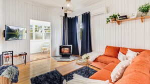 A cozy living room with a fireplace, a sofa, and a television. - Cheerful, Cosy Cottage - Near Rose Garden! (Newtown)