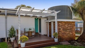 A covered outdoor area with a wooden deck, a brick wall, and a pergola. - Cheerful, Cosy Cottage - Near Rose Garden! (Newtown)