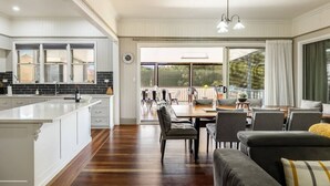 A spacious kitchen with a large island, a dining area with a table and chairs, and a cozy seating area with a sofa. - Elegant, Stunning & Central! East Side Gem! (East Toowoomba)