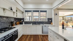 A modern kitchen with white cabinetry, a black tiled backsplash, a built-in stove, and a large window providing natural light. - Elegant, Stunning & Central! East Side Gem! (East Toowoomba)
