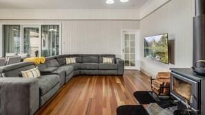 A modern living room with a sectional sofa, a fireplace, and a television mounted on the wall. - Elegant, Stunning & Central! East Side Gem! (East Toowoomba)