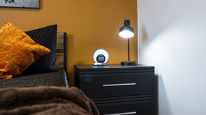 A bed with a patterned pillow, a bedside table with a digital clock, and a desk lamp. - New! Hippy Haven Suite in East! 4bd! (Nashville)