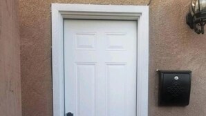 A private entrance to a studio with a white door, a doormat, and a wall-mounted mail slot. - Private Studio (San Bernardino)