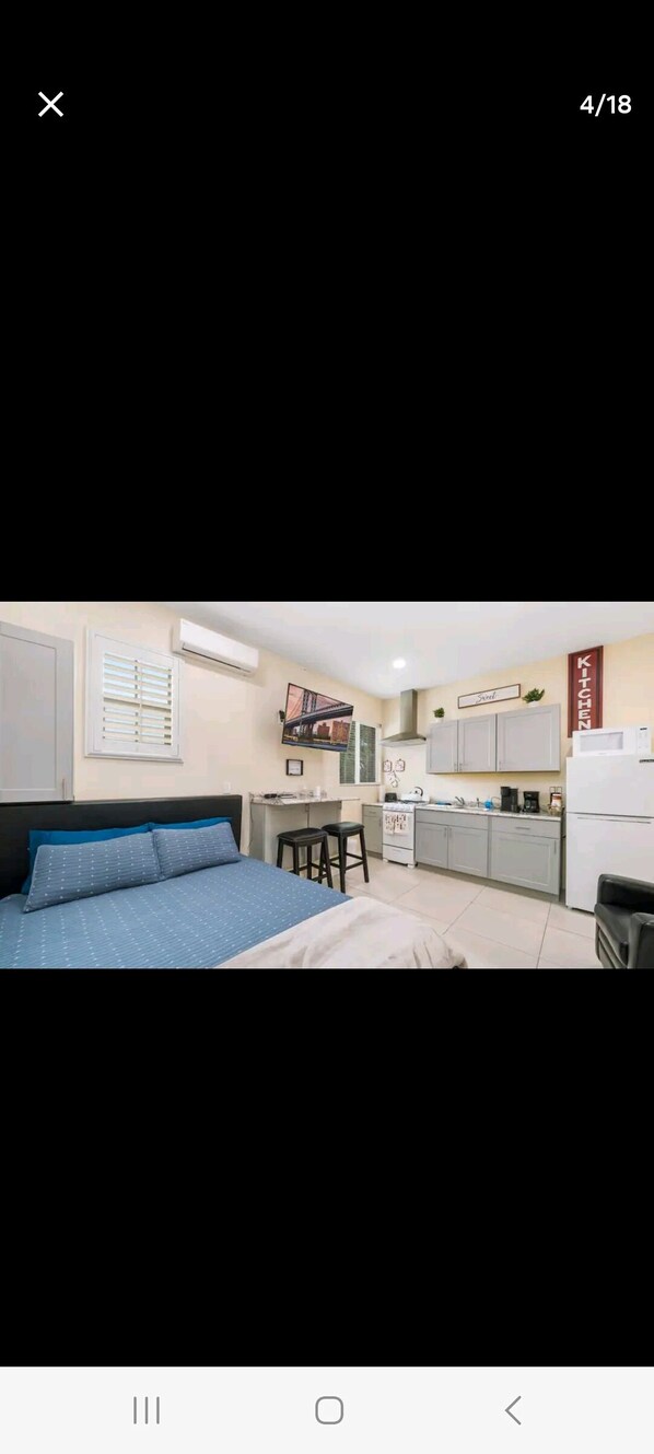 A compact room with a bed, a kitchenette, and a small dining area.