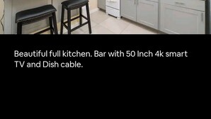 A full kitchen with a bar area, a 50-inch 4K smart TV, and a dish cable. - Private Studio (San Bernardino)