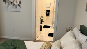 Een slaapkamer met een groene sprei, witte lakens en een afstandsbediening op het bed.