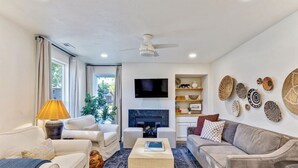 A living room with a fireplace, sofas, a coffee table, and decorative wall art. - Sunset Paradise Retreat | 2 Hot Tubs | 2 Houses (Orem)