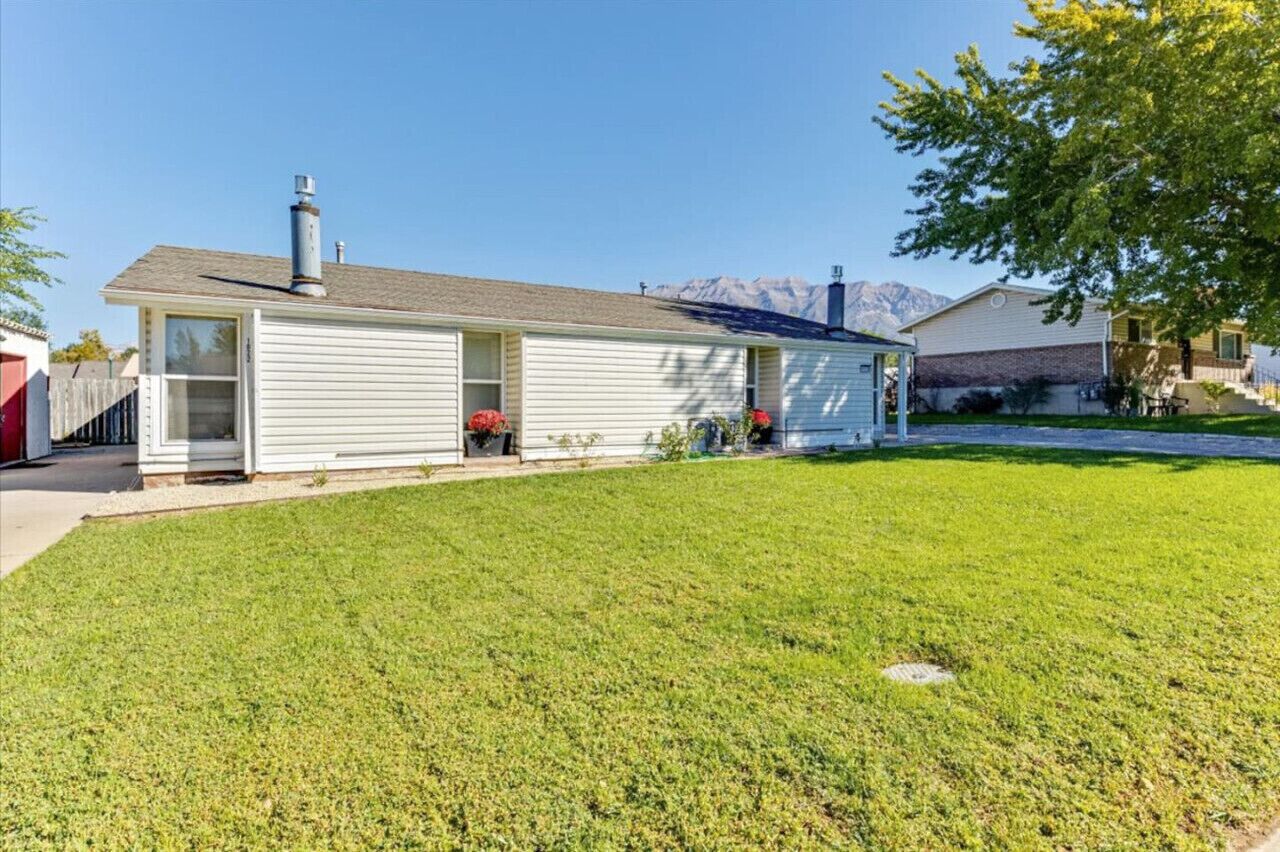 A single-story house with a chimney, a front porch, and a well-maintained lawn.