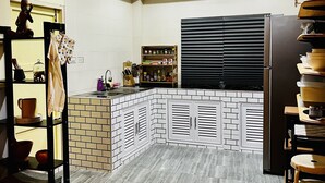 A modern kitchen with a built-in island, white subway tiles, and a black refrigerator. - Seaside home for families and furry friends! (Pranburi)