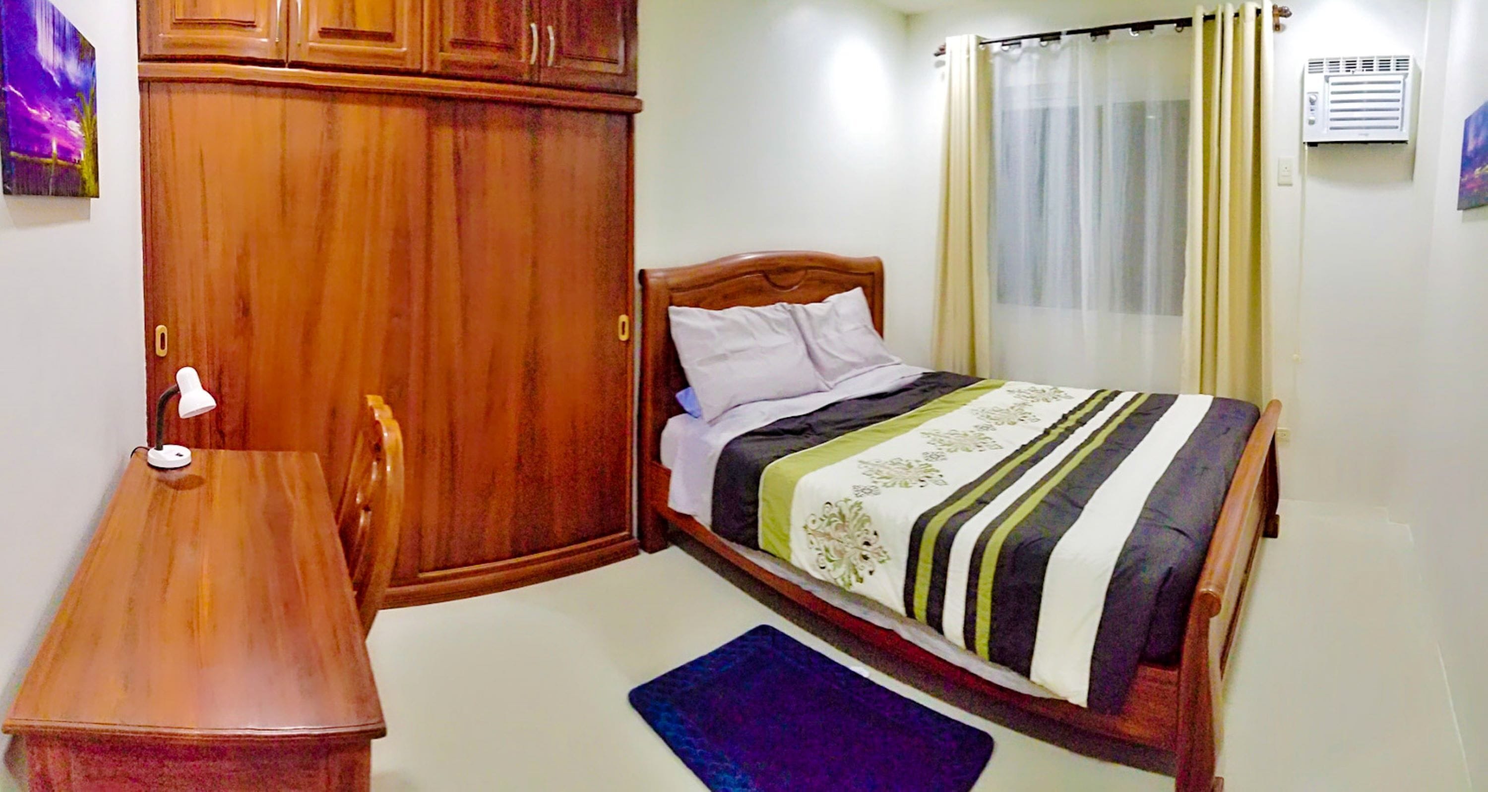 Quarto com uma cama de madeira, uma escrivaninha e uma cadeira.