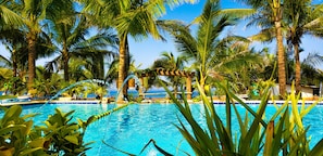 A swimming pool surrounded by palm trees and a clear blue sky. - Crystal Shore Beach Resort powered by Cocotel (Morong)