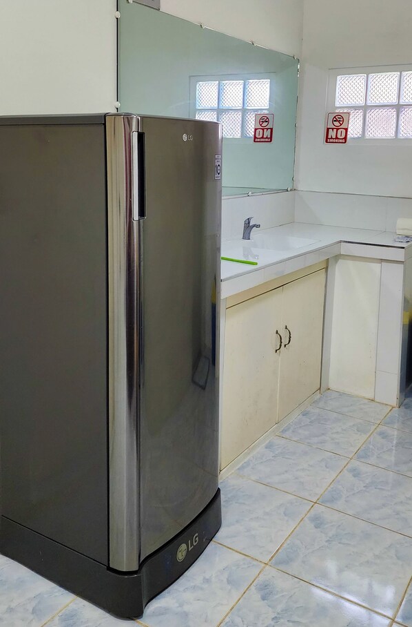 A kitchen with a stainless steel refrigerator, a sink, and cabinets.