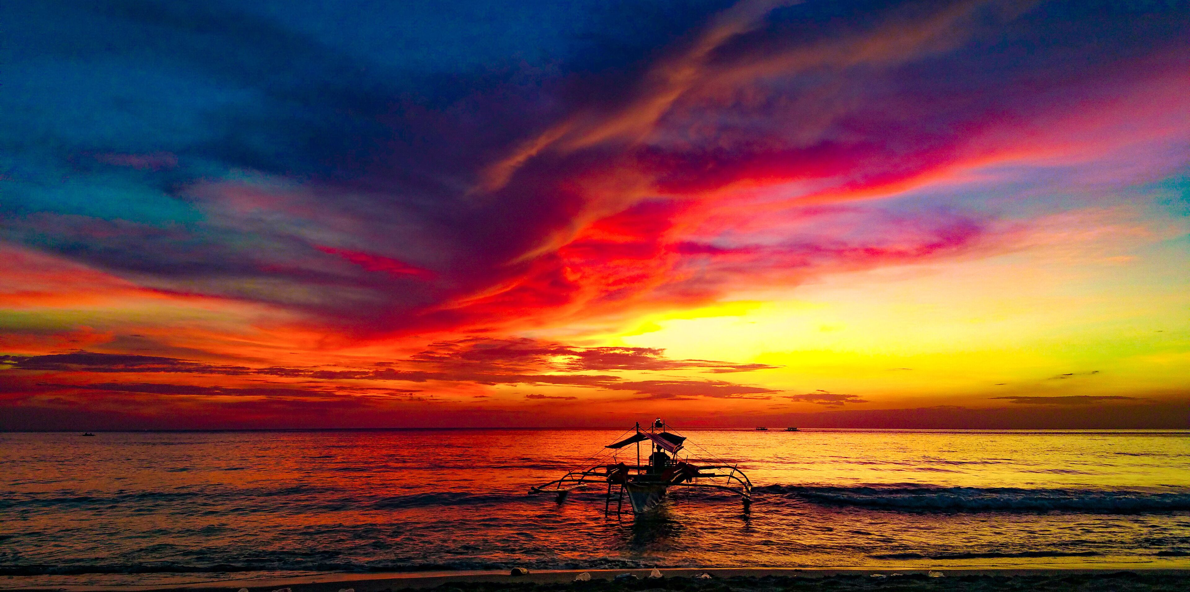 Un atardecer sobre el océano con un barco en primer plano.