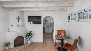 A modern interior with a fireplace, a dining area with a table and chairs, and a kitchen visible through an archway.