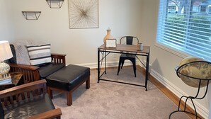 Ein gemütliches Wohnzimmer mit einer Couch, einem Couchtisch und einem Esstisch. An den Wänden sind Leuchten angebracht und es steht ein Globus auf einem Stativ.