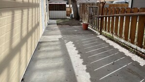 Ein überdachter Außenbereich mit einem Betonweg, einem Holzzaun und Lichterketten.