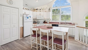 A kitchen with a central island, white cabinetry, a microwave, and a clock on the wall. - Casa Sonada II - 4 BR Beach Home in Quiet, Low Traffic Neighborhood, Dogs Allowed (Southern Shores)