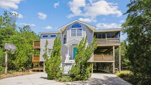 A two-story house with a front porch, a covered deck, and a small front yard. - Casa Sonada II - 4 BR Beach Home in Quiet, Low Traffic Neighborhood, Dogs Allowed (Southern Shores)