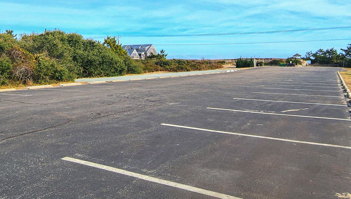 Un parking vide, avec des emplacements de stationnement délimités, et un bâtiment en arrière-plan.