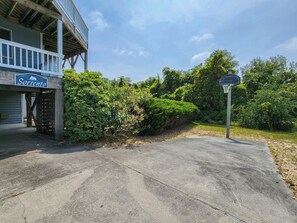 A basketball court with a hoop, surrounded by greenery and a building with a sign reading "Sorrento". - Sorrento - Enjoy Sound Views from this Soundside Home w/Private Pool (Southern Shores)