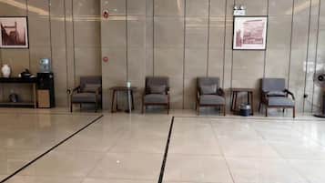 A reception area with a reception desk, several chairs, a small table, and a wall-mounted fan.