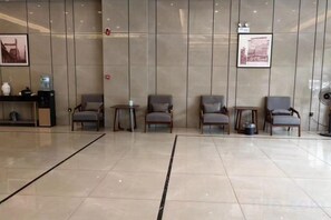A reception area with a reception desk, several chairs, a small table, and a wall-mounted fan. - Fengle Yiting Hotel (Huangshan Yansi Scenic Area) (Huangshan City)