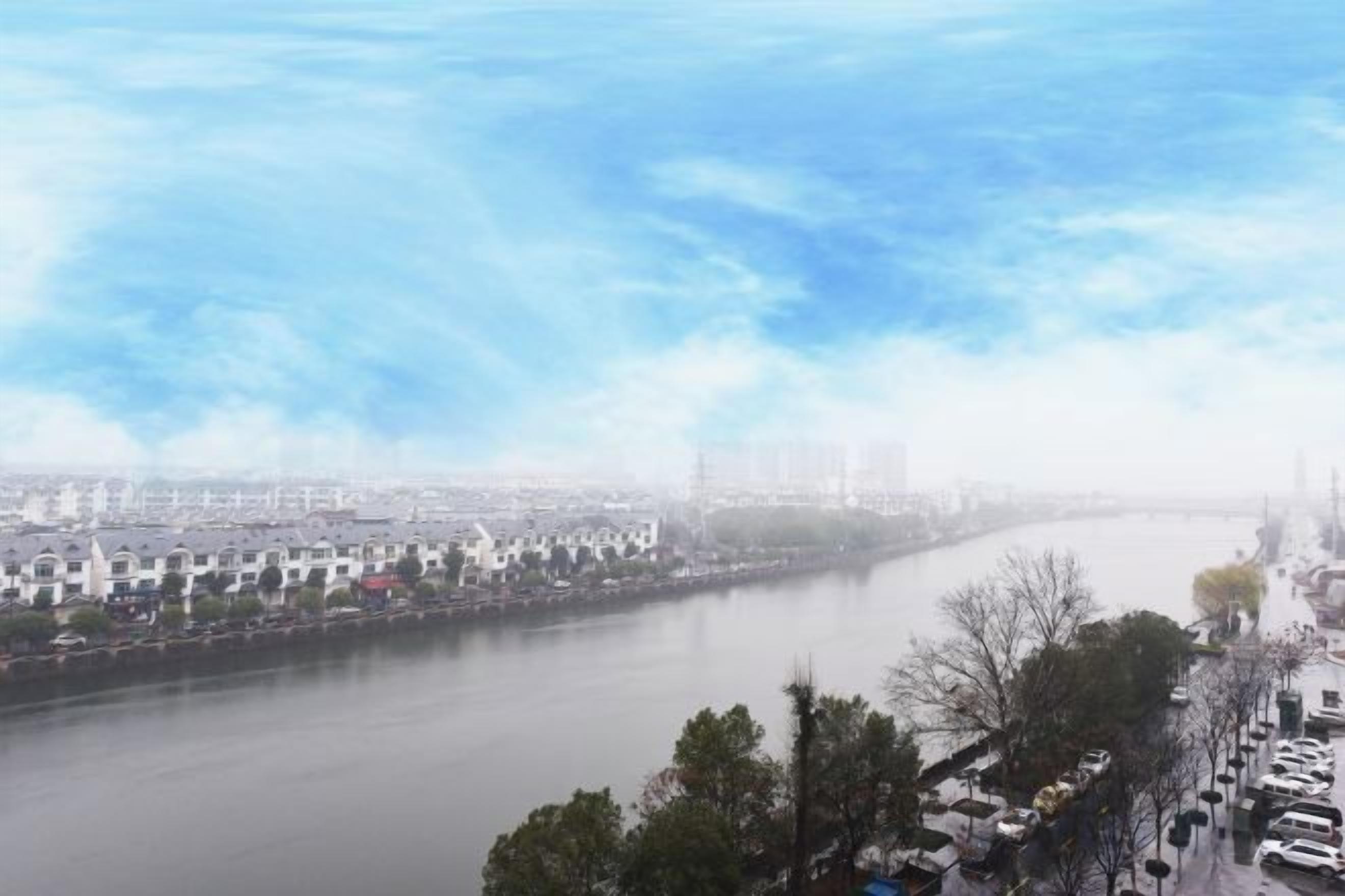 A river with buildings on one side and trees on the other.