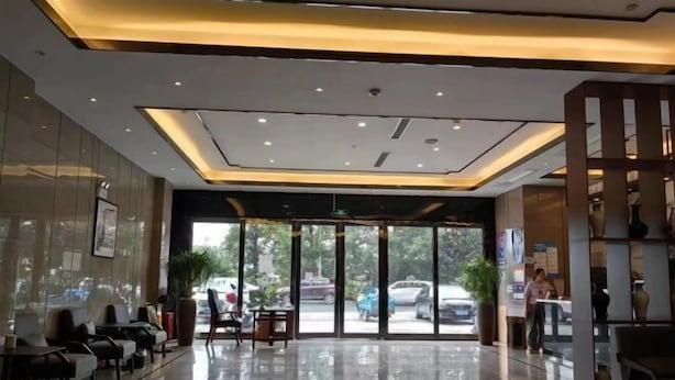 A hotel lobby with a glass entrance, seating area, and a reception desk.