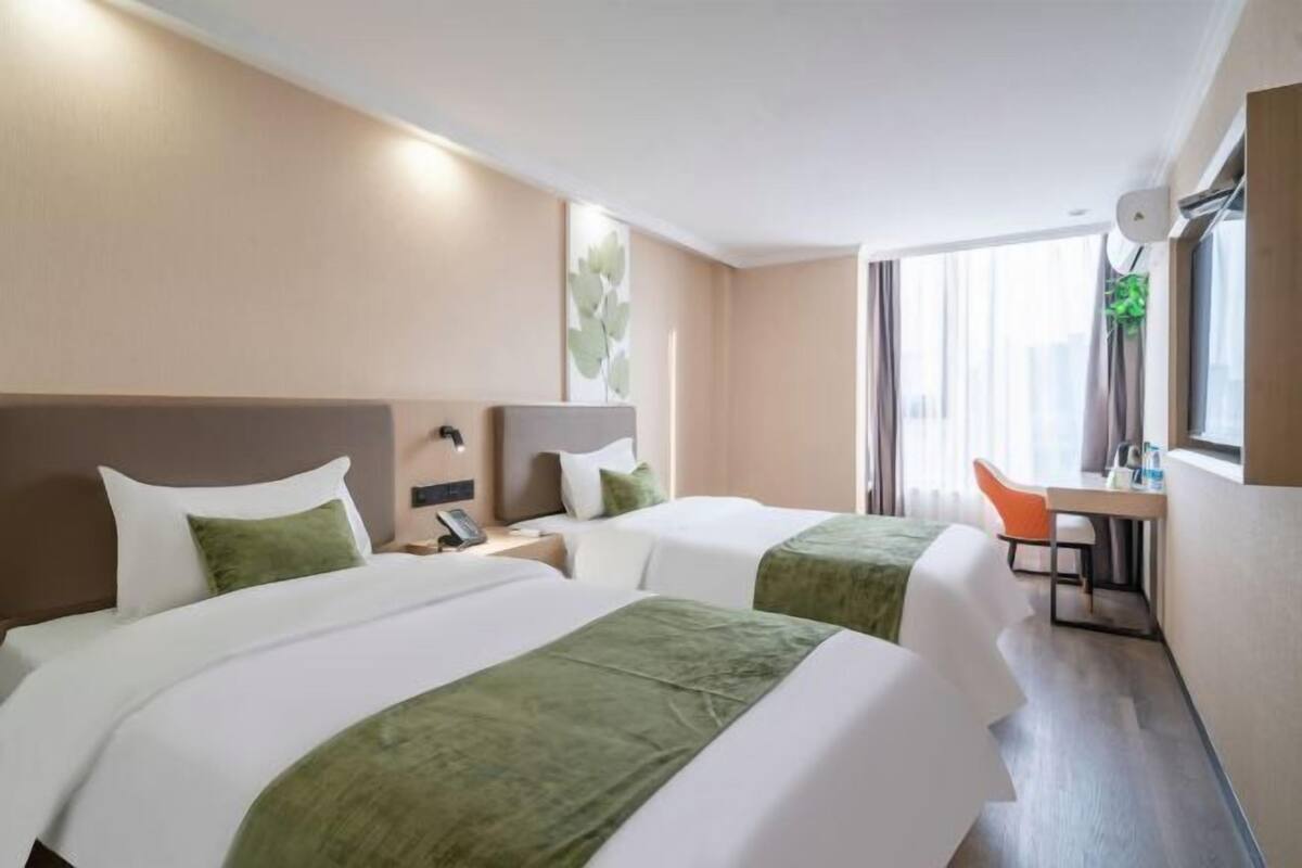 A hotel room with two beds, a desk, and a chair.