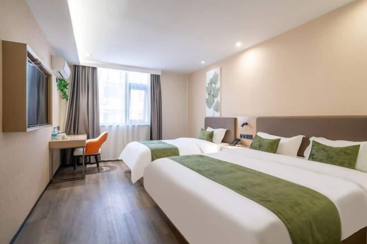 A hotel room with two beds, a desk, and a chair.