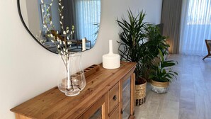 A wooden console table with a clear vase, a white object, and potted plants. - Garajau Apart with Amazing Views, Parking & Wifi. (Caniço)