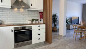 A modern kitchen with white cabinetry, a stainless steel range hood, and a built-in oven. There is a wooden countertop with a few potted plants. - Garajau Apart with Amazing Views, Parking & Wifi. (Caniço)