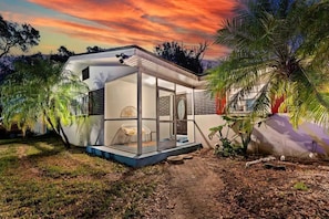 Una casa moderna con struttura in vetro, un vialetto e vegetazione circostante.