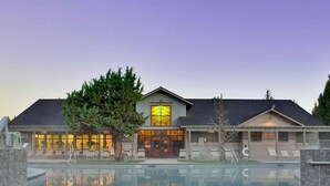 A modern hotel with a large outdoor pool, a covered patio, and a well-maintained landscape. - 19th Hole Chalet - Eagle Crest Resort (Redmond)