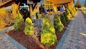 A lodge with a stone chimney, a covered patio, and neatly trimmed bushes. - 19th Hole Chalet - Eagle Crest Resort (Redmond)